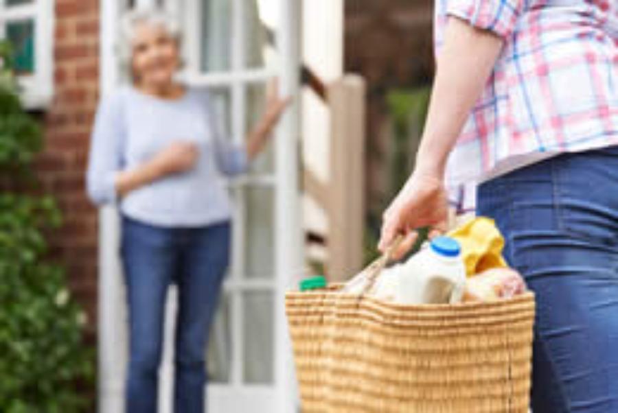 Woman bringing groceries to older woman Woman bringing groceries to older woman